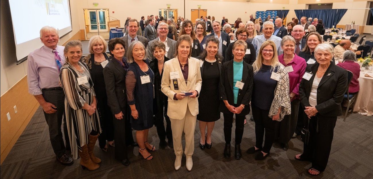 Lisa Holmes in a suit surrounded by collegues
