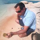Image of a man examining a sponge along the shore.
